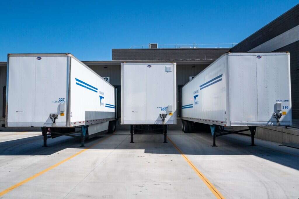 White cargo trailers parked at an industrial shipping dock under a clear sky