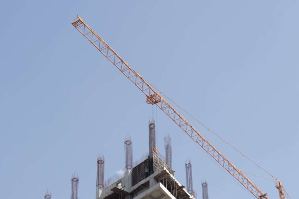 Tower crane working above a high-rise construction site against a blue sky