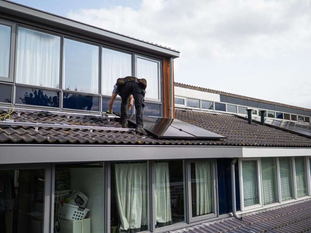 Technician installing solar panels on a rooftop in daylight