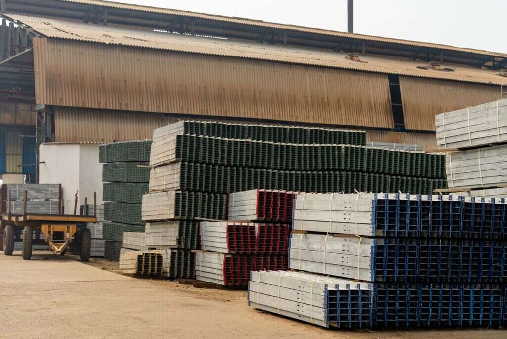 Outdoor materials yard with stacked metal beams and palletised building supplies