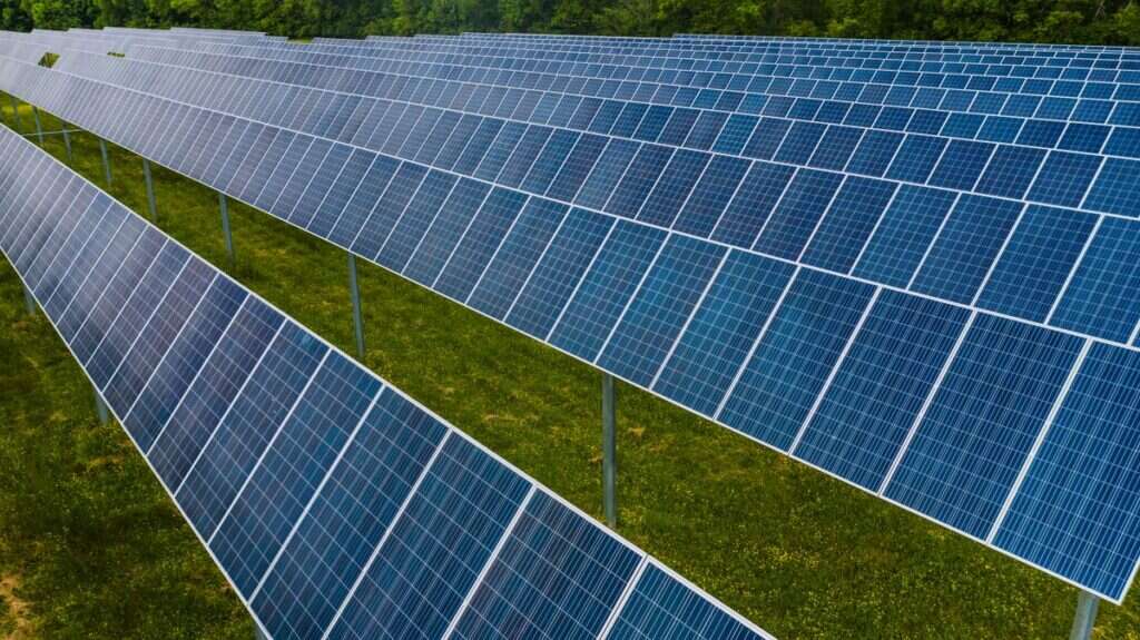 Rows of blue photovoltaic solar panels mounted over a grassy field