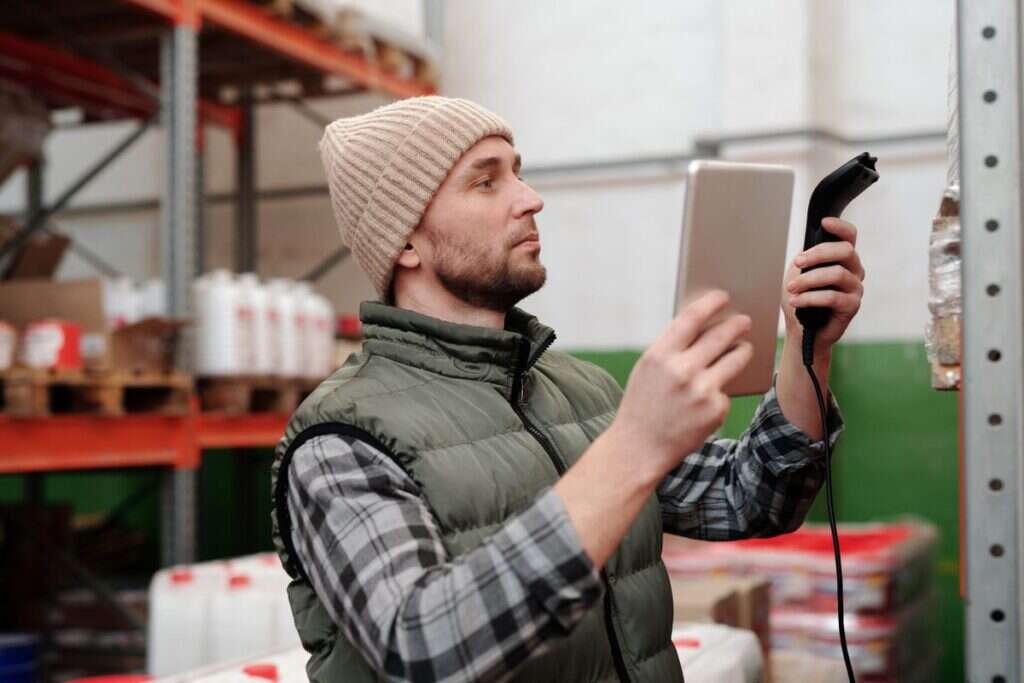 Warehouse operative using a scanner for stock control beside racking